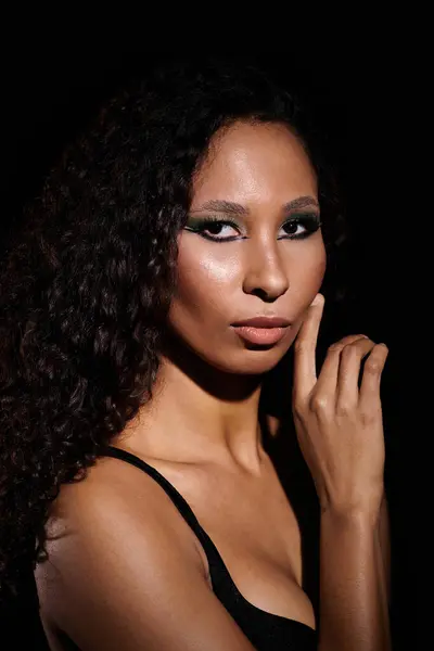 Beautiful woman with curly hair poses gracefully against a dark backdrop, exuding confidence. — Stock Photo