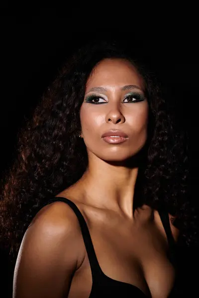 A beautiful woman showcases her stunning features and exquisite makeup in soft lighting. — Stock Photo