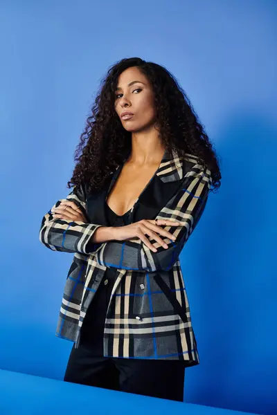 A confident woman stands with crossed arms, showcasing her beauty and strong presence in a blazer. — Stock Photo
