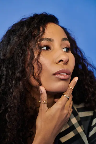 A woman with stunning curls showcases delicate rings, deep in thought and exuding confidence. — Stock Photo