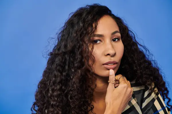A thoughtful woman displays her unique style against a rich blue backdrop. — Stock Photo