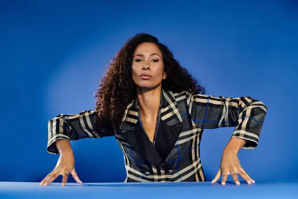 A stylish woman exudes confidence against a striking blue backdrop. — Stock Photo