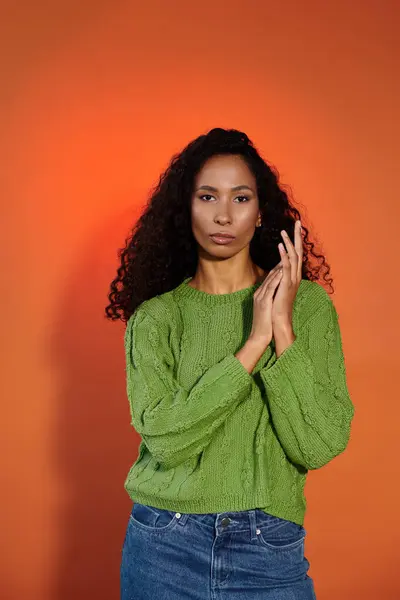 The woman in the green sweater catches the eye against a vibrant orange backdrop. — Stock Photo