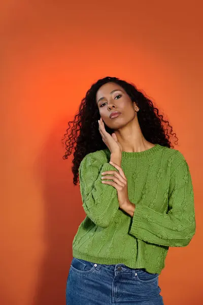 A stunning woman with curly hair confidently showcases a vibrant sweater and striking pose. — Stock Photo