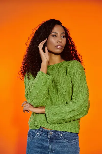 A stunning woman with flowing curls showcases elegance while adorned in a vibrant green sweater. — Stock Photo