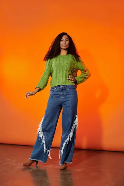Stunning woman displays fashion confidence with a chic green sweater and trendy jeans at sunset. — Stock Photo