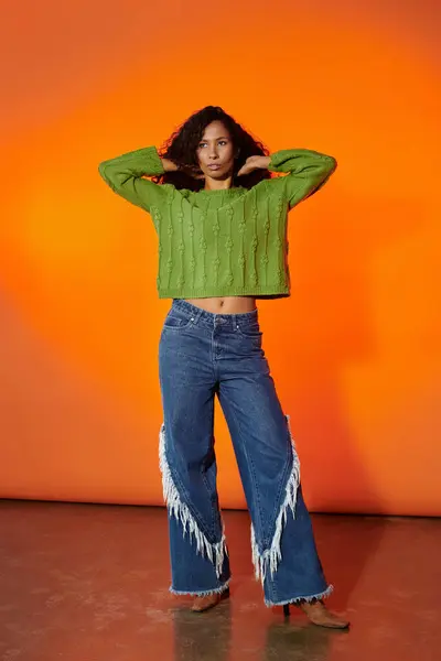 A confident woman showcases her unique fashion sense, posing against an orange backdrop. — Stock Photo