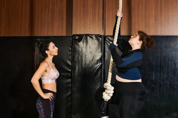 Two women focus on a challenging rope climb, showcasing support and teamwork in their training. — Stock Photo