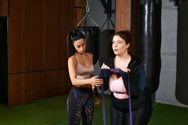 Femmes dédiées mettent en valeur le travail d'équipe et la motivation tout en se concentrant sur la forme physique dans la salle de gym. — Photo de stock