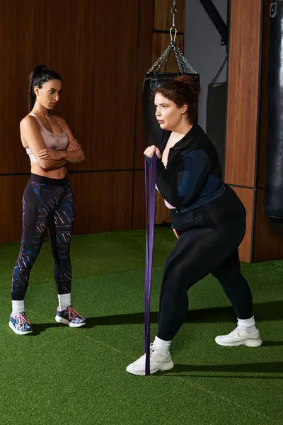 Deux femmes dans un cadre de gymnastique, une formation avec des bandes de résistance tout en recevant des encouragements. — Photo de stock