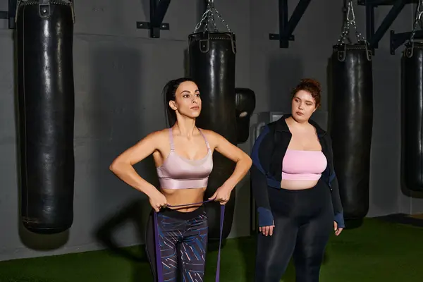 Two women focus on their workout routines in a gym, promoting fitness and teamwork. — Stock Photo