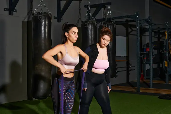 Two women are focused on their workout with resistance bands inside a trendy gym space. — Stock Photo
