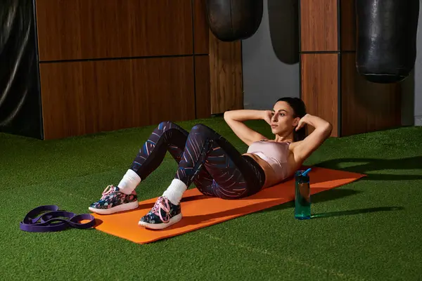 Woman performing abdominal exercises on a vibrant mat while engaging in a focused workout. — Stock Photo