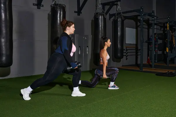 Due donne che eseguono affondi con pesi in una moderna palestra incentrata sul fitness. — Foto stock