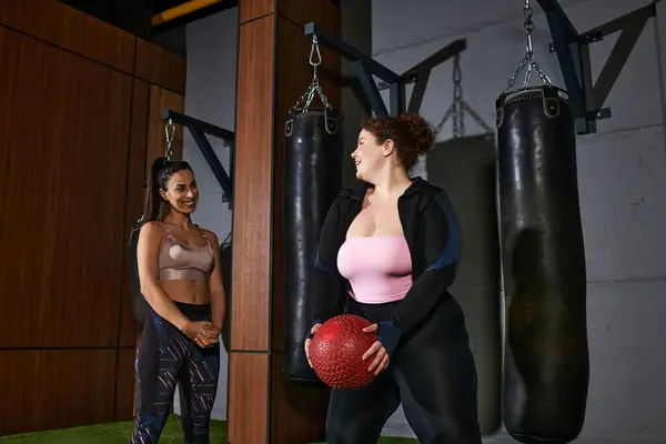 Two women engage in an energetic workout, lifting weights and motivating each other in the gym. — Stock Photo