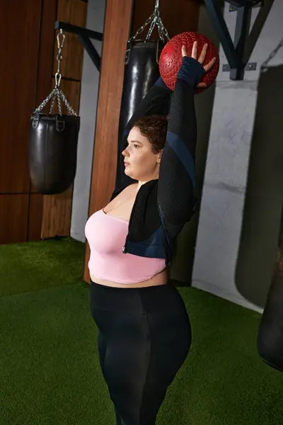 Engaging in a challenging exercise routine with a heavy ball in a vibrant gym setting — Stock Photo