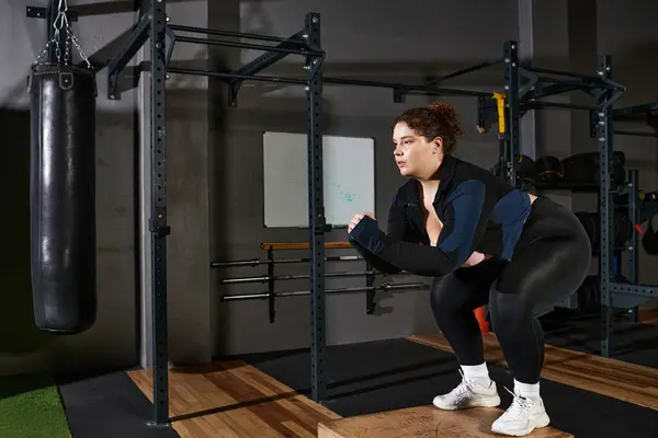 Femme s'engage dans des exercices de squatting concentrés sur une plate-forme robuste dans une salle de gym. — Photo de stock