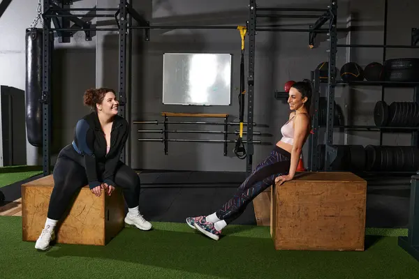 Two friends are enjoying a break while exercising at a gym, sharing laughs and motivation. — Stock Photo