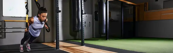 Mujer realiza flexiones de suspensión en un gimnasio bien equipado durante una sesión de entrenamiento. — Stock Photo