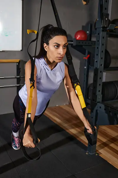Woman enhances strength and stability through suspension training in a well equipped gym. — Stock Photo