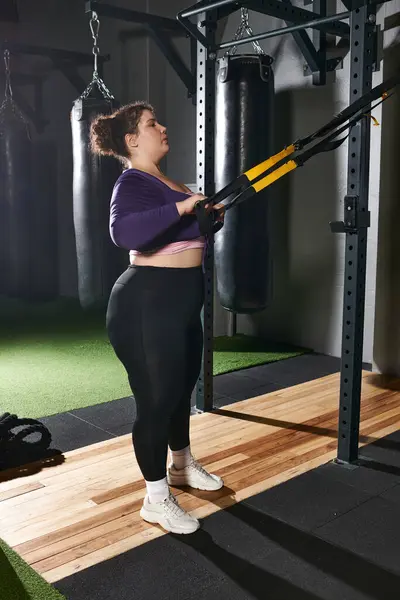 Una mujer enfocada se involucra en entrenamiento de fuerza usando equipo en un vibrante entorno de gimnasio. — Stock Photo
