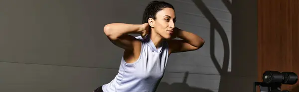 Dedicated woman performing a dynamic exercise in a sleek gym setting during morning hours. — Stock Photo