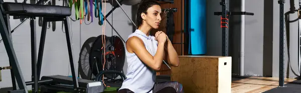 Dedicated woman engages in a focused squat exercise in a well equipped gym space. — Stock Photo