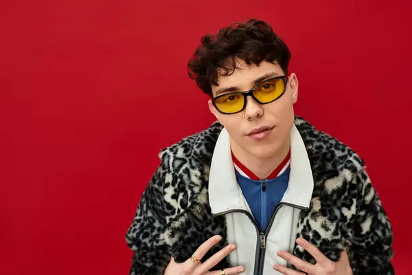 Handsome man showcases unique style with yellow glasses and animal print coat in a bold setting. — Stock Photo