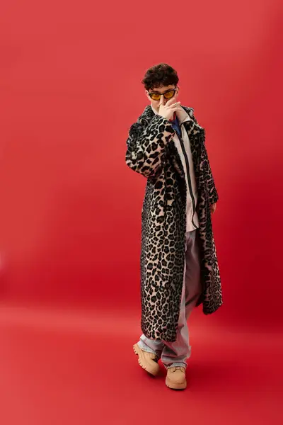 Handsome man showcases a unique fashion sense with flair in front of a bold red background. — Stock Photo