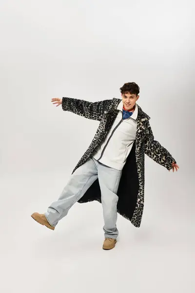 Stylishly dressed man in oversized coat poses playfully under studio lights. — Stock Photo