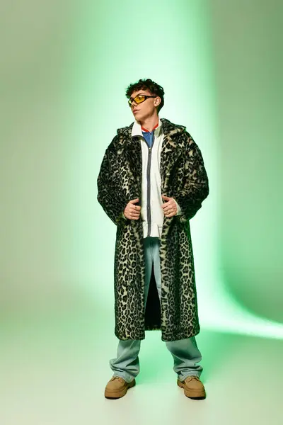Schöner Mann posiert selbstbewusst in schickem Animal-Print-Mantel mit auffallend grünem Hintergrund. — Stockfoto