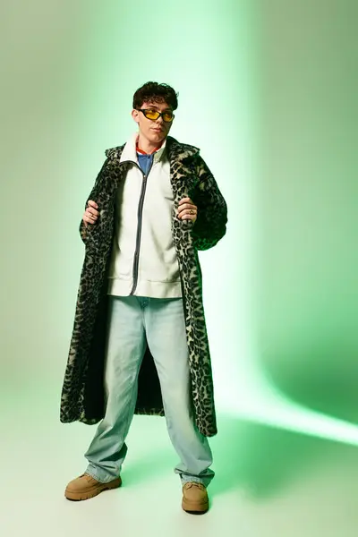 Schöner Mann präsentiert einzigartige Mode im trendigen Outfit vor grünem Hintergrund. — Stockfoto