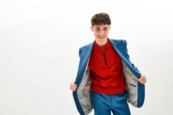 Hombre guapo vestido con un traje vívido sonríe mientras abre su chaqueta, exudando encanto y estilo. - foto de stock