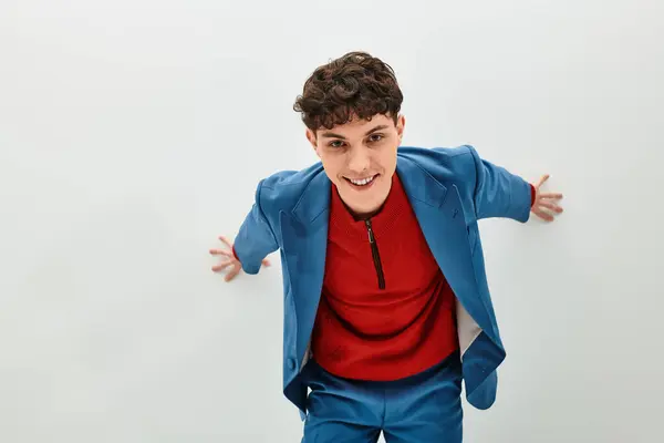 Hombre guapo en un traje vibrante expresa confianza con una postura juguetona contra una pared lisa. - foto de stock