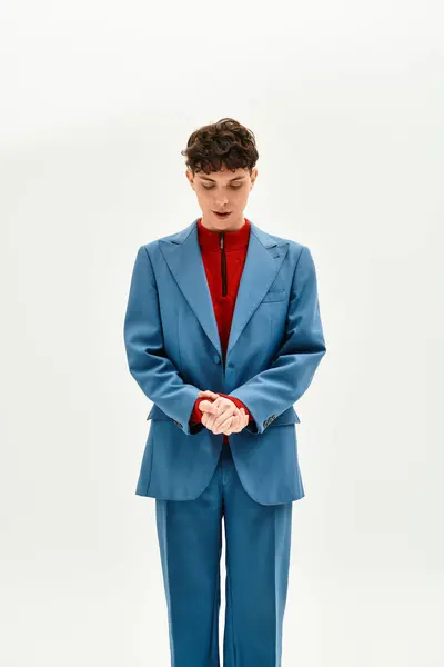 Handsome man dressed in a blue suit and red sweater captivatingly poses in a clean, bright space. — Stock Photo