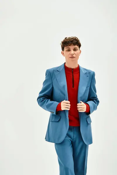 Young man charms in a striking blue suit and red sweater against a light background. — Stock Photo