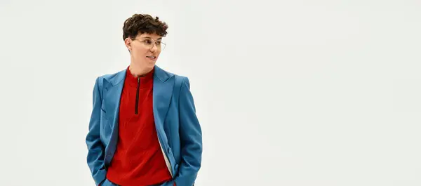 A handsome man stands confidently in a chic outfit, blending vibrant hues against a soft backdrop. — Stock Photo