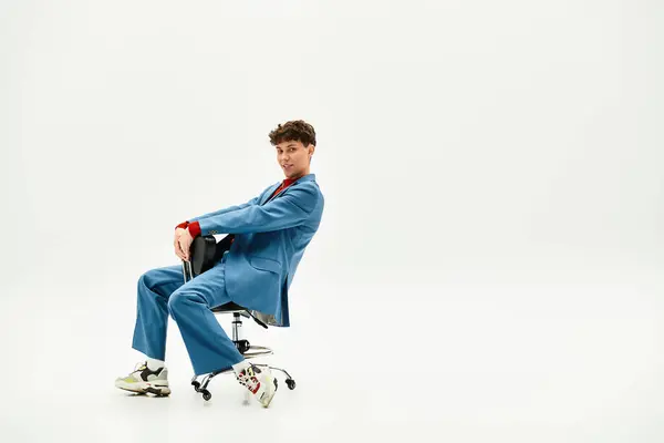 Handsome gentleman leans back playfully in a rolling chair, showcasing bold fashion choices. — Stock Photo