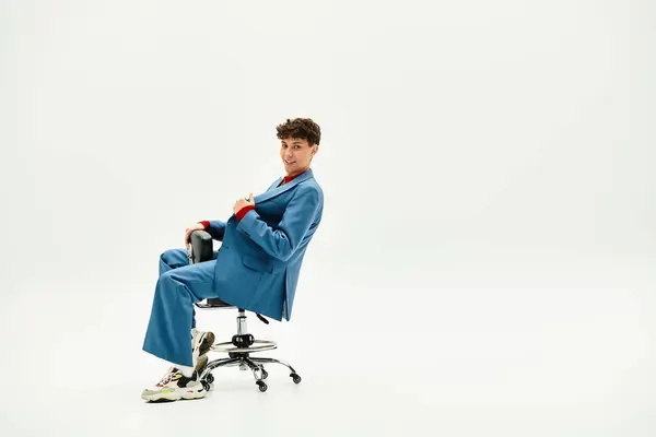 Handsome man dressed in a stylish suit strikes a pose while seated in a swivel chair — Stock Photo
