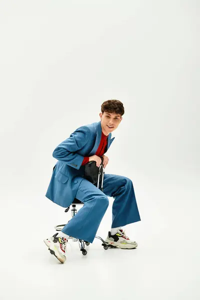 A stylish man in a blue suit and red shirt sits on a swivel chair. — Stock Photo