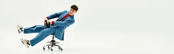 Handsome man in a stylish suit spins playfully on a chair in an airy and bright office. — Stock Photo