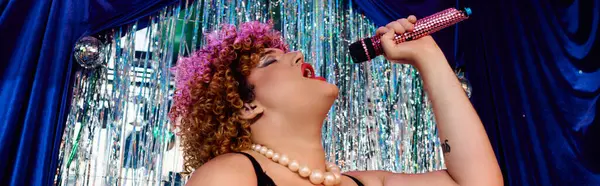 A drag queen captivates the crowd with stunning makeup and powerful vocals in a festive vibe. — Stock Photo