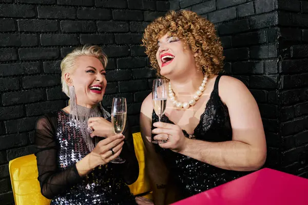 Due drag queen in abiti stravaganti condividono risate e bicchieri di champagne — Foto stock