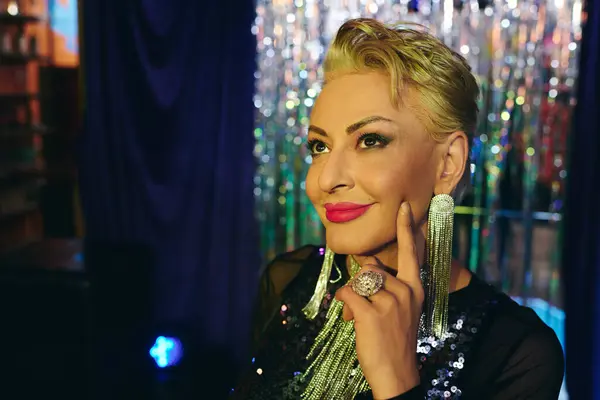 A dazzling drag queen shines on stage with bold makeup and charisma at a festive event. — Stock Photo