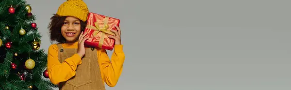 Jeune fille brille de joie, tenant un cadeau joliment emballé à Noël. — Photo de stock