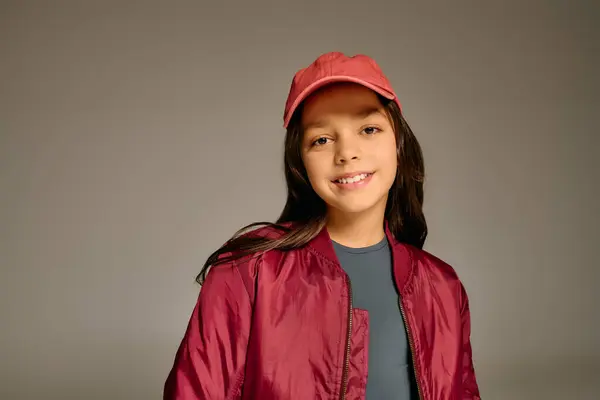 Little girl in red jacket and cap beams joyfully, embodying the spirit of Christmas 2025. — Stock Photo