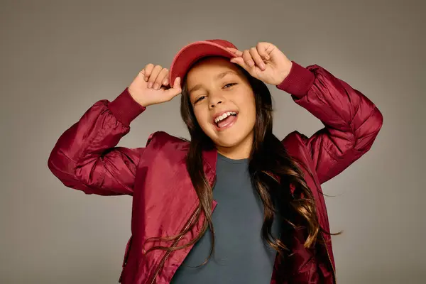 A cheerful girl wearing a red cap and jacket happily engages in Christmas festivities. — Stock Photo