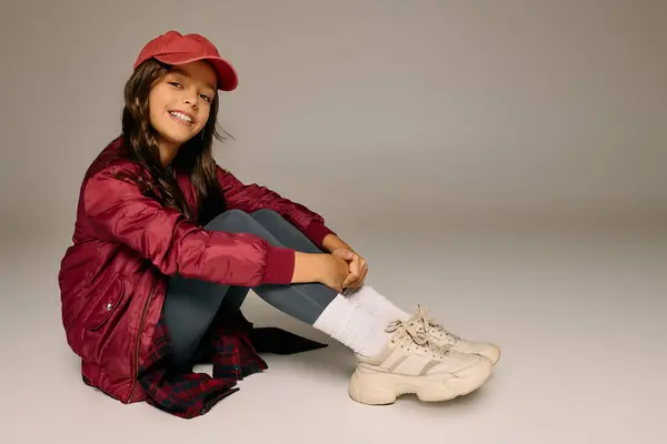 Menina vestida com cores de Natal irradia felicidade enquanto sentado confortavelmente. — Fotografia de Stock