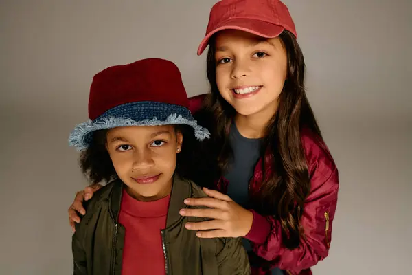 Due allegre bambine che indossano cappelli festivi condividono sorrisi e gioia durante il Natale 2025. — Foto stock