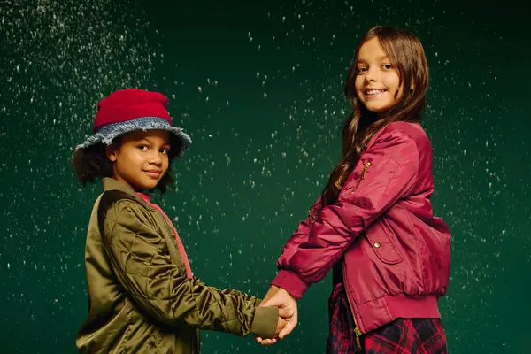 Two girls embrace the joy of Christmas, holding hands and smiling amid falling snow. — Stock Photo